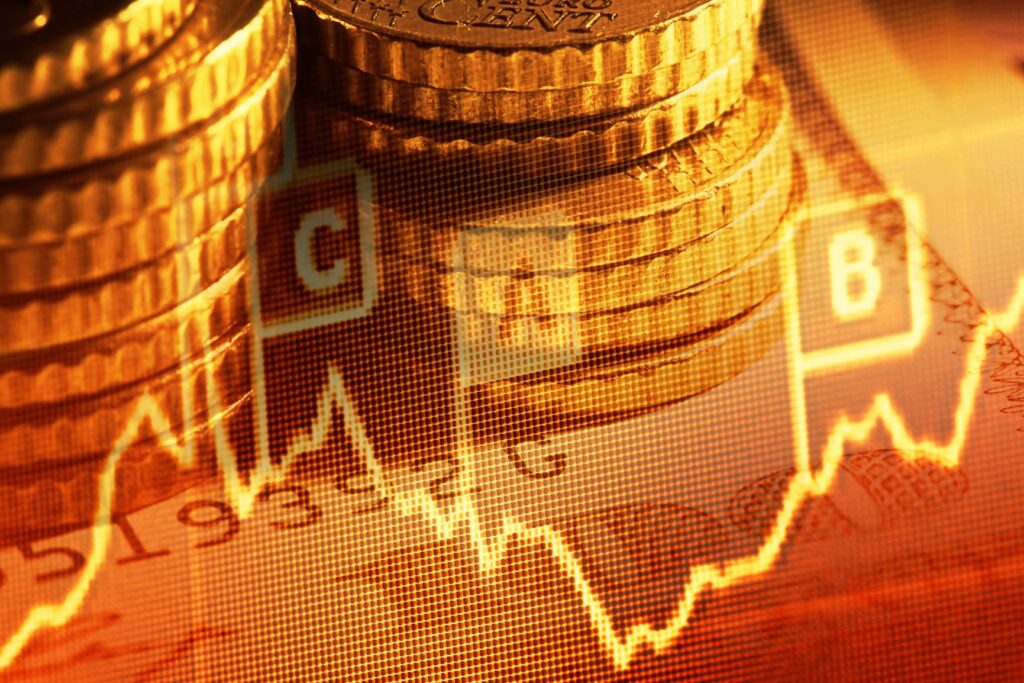 Pile di monete sovrapposte a un grafico di borsa fluttuante e a dati finanziari, che simboleggiano investimenti, crescita economica o analisi di mercato. L'immagine ha una tonalità calda e dorata.