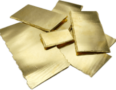 Diversi fogli sottili e rettangolari di metallo lucido e color oro sono impilati e sparsi su una superficie piana.