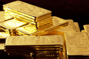 Un mucchio di lingotti d'oro lucidi impilati l'uno sull'altro su uno sfondo scuro.