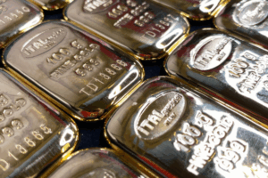 Diversi lingotti d'oro lucidi sono disposti l'uno accanto all'altro, ognuno dei quali reca la scritta "ITALPREZIOSI", "100 g", "ORO FINE 999,9" e un numero di serie univoco sulla superficie riflettente.