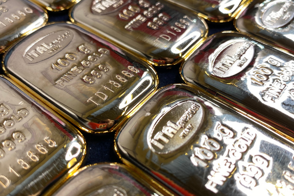 Diversi lingotti d'oro lucidi sono disposti l'uno accanto all'altro, ognuno dei quali reca la scritta "ITALPREZIOSI", "100 g", "ORO FINE 999,9" e un numero di serie univoco sulla superficie riflettente.