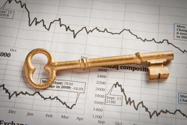 Una chiave d'oro poggia su un grafico del mercato azionario stampato che mostra dati finanziari fluttuanti, evidenziando la volatilità e gli eventi significativi del mercato nel tempo.