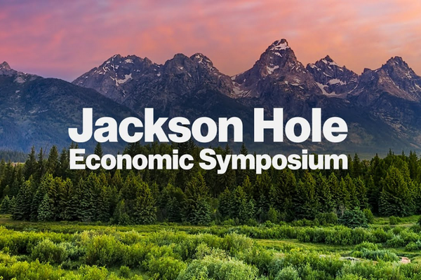 Text Jackson Hole Economic Symposium over a scenic landscape with dense green trees in the foreground and rugged mountain peaks beneath a colorful sky in the background.