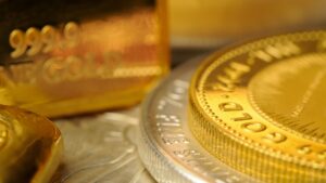 Primo piano di lingotti d'oro e monete d'oro, con iscrizioni dettagliate come 999.9 FINE GOLD visibili, che evidenziano le loro superfici lucide e riflettenti.