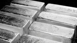 A close-up of several shiny silver bars stacked together, showing their textured surfaces and metallic sheen.