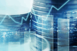 Pile di monete con grafici a linee ascendenti sovrapposte, che simboleggiano la crescita finanziaria, gli investimenti o il progresso economico. Sullo sfondo è leggermente visibile un paesaggio urbano.