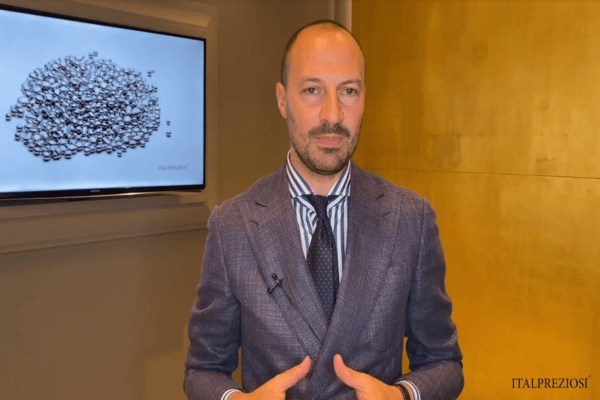 Un uomo in abito blu si trova al chiuso davanti a uno schermo che visualizza una pila di piccoli oggetti. La parete di sfondo è giallastra e l'immagine reca la scritta ITALPREZIOSI nell'angolo in basso a destra.