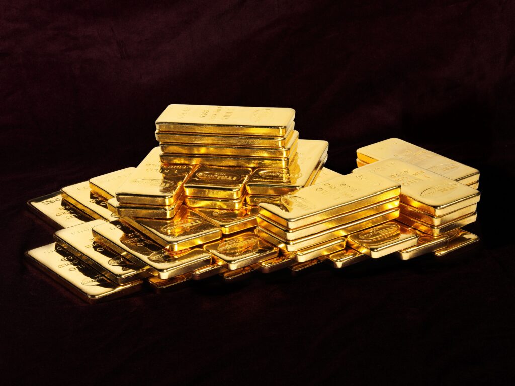 Le pile di lingotti d'oro lucidi sono disposte su una superficie scura e le loro superfici riflettenti catturano la luce.