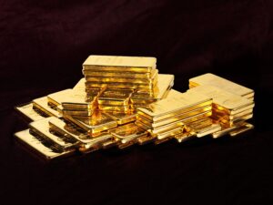 Le pile di lingotti d'oro lucidi sono disposte su una superficie scura e le loro superfici riflettenti catturano la luce.