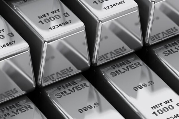 Vista ravvicinata di più lingotti d'argento lucido, ciascuno etichettato come FINE SILVER 999.9 e NET WT 1000 g, disposti in file ordinate.