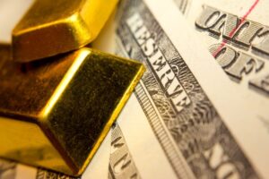 Primo piano di due lingotti d'oro appoggiati su banconote da un dollaro americano, che evidenziano la scritta RESERVE e suggeriscono i temi della ricchezza, della finanza e dell'investimento.
