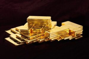 Le pile di lingotti d'oro lucidi sono disposte su una superficie scura, riflettendo la luce e creando un aspetto ricco e lussuoso.