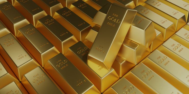 Pile di lingotti d'oro lucidi disposti l'uno vicino all'altro, con alcuni lingotti impilati in modo ordinato e altri leggermente distorti. Su ogni lingotto sono incise le diciture FINE GOLD e 999.9, a indicare l'elevata purezza.