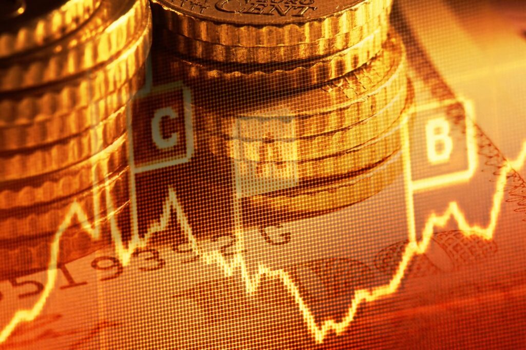 Sullo sfondo sono raffigurate pile di monete con un grafico finanziario sovrapposto, caratterizzato da un grafico a linee fluttuanti e da simboli di valuta, che simboleggiano la crescita economica e i mercati finanziari.