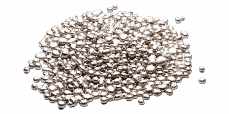 Un mucchio di piccoli pallini metallici argentati e lucenti sparsi su una superficie bianca.